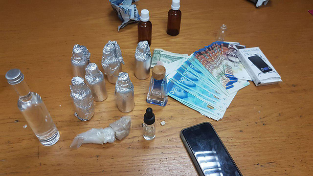 בקבוקי הסם וכסף מזומן שאותרו בבית החשוד (צילום: דוברות המשטרה) (צילום: דוברות המשטרה)