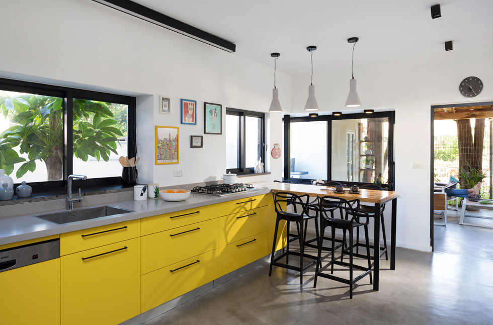 בקצה ציר ארונות המטבח הצהובים הותקן שולחן אוכל גבוה עשוי פלטת עץ בוצ'ר. בחוץ פינת ישיבה אינטימית (צילום: שי אפשטיין)