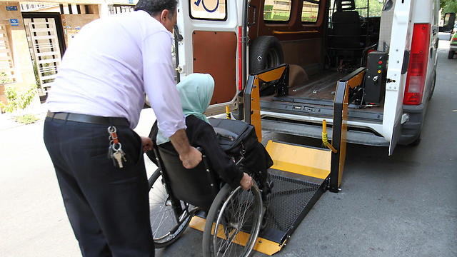 פטמה נקבחט, שאיבדה את רגליה בתאונה בשנות ה-90, מועלית לרכב הסעות לנכים (צילום: AFP) (צילום: AFP)