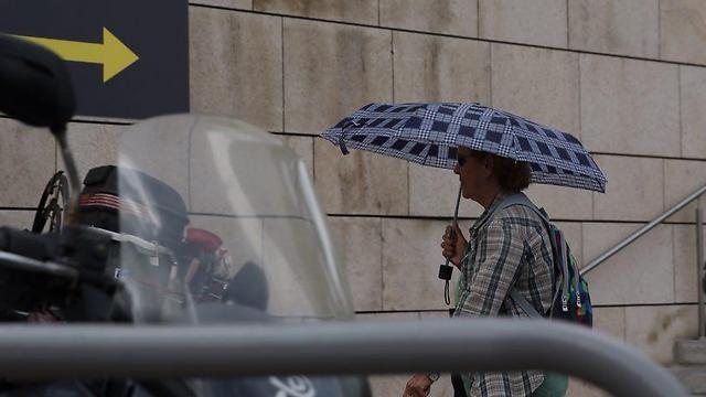 מתגוננים מפני הגשם בתל אביב (צילום: מוטי קמחי) (צילום: מוטי קמחי)