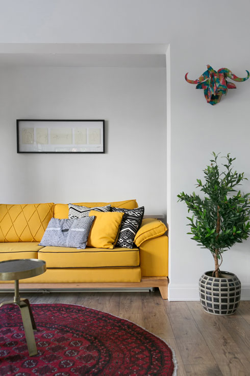בסלון: ספה צהובה, שטיח אליפטי ושולחנות קטנים  (צילום: שירן כרמל)