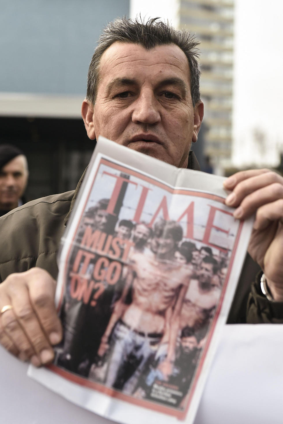 פיקרט אליץ', ששרד את הטבח, מחזיק גיליון של מגזין "טיים" עם תמונתו על השער (צילום: AFP) (צילום: AFP)