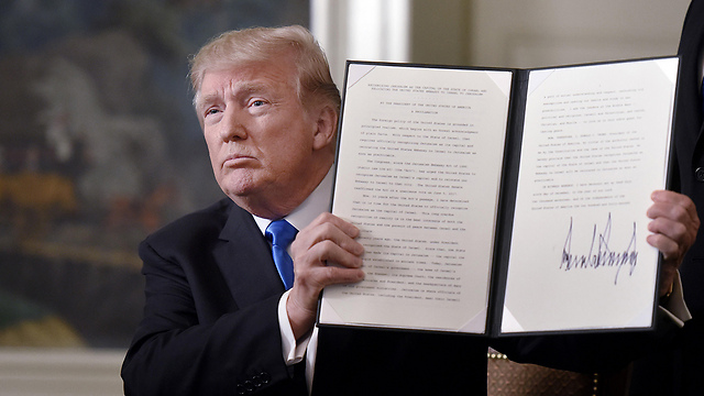 Trump showing his signature on the presidential decree postponing the US embassy move to Jerusalem (Photo: Reuters)