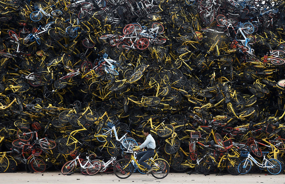 רוכב ליד הר אופניים שיתופיים במגרש בסין (צילום: רויטרס) (צילום: רויטרס)