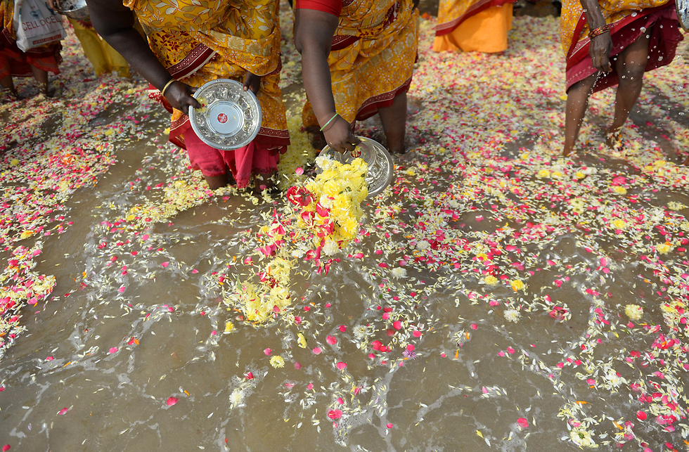 הודיות זורקות פרחים לים לזכר קורבנות אסון הצונאמי של שנת 2004 (צילום: AFP) (צילום: AFP)
