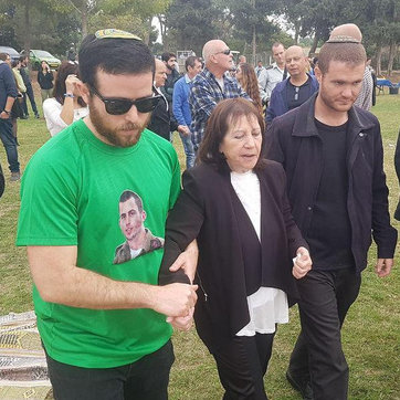Zehava Shaul led away from the ceremony in honor of her son after rockets are fired from Gaza  (Photo: Moti Lavton)