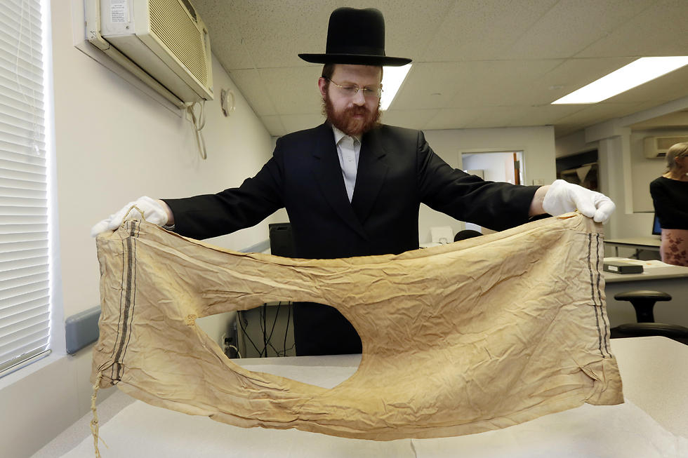 Dovid Reidel holds a talit, or prayer shawl, part of the museum's collection, that belonged to Mendel Landau, in 1944, of Auschwitz, Poland (Photo: AP)