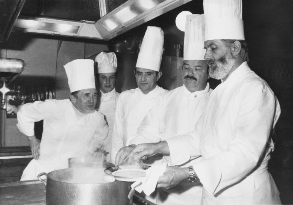 פול בוקוז מכין ארוחת ערב נשיאותית במטבחי ארמון האליזה בפריז, לאחר שזכה באות הליגיון הצרפתי מנשיא צרפת בשנת 1975 (  ) (  )