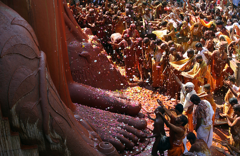 חסידי דת הג'יין זורקים פרחים על פסל קדוש בשראוואנבלגולה, הודו (צילום: AP) (צילום: AP)