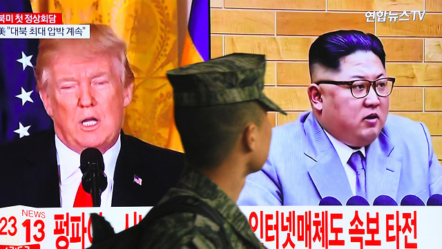 חייל דרום קוריאני בסיאול חולף על פני מסך טלוויזיה ובו דמויות מנהיגי ארה"ב וצפון קוריאה (צילום: AFP) (צילום: AFP)