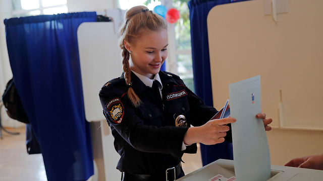 צוערת משטרה מצביעה בבחירות לנשיאות רוסיה בקלפי במוסקבה (צילום: AP)
