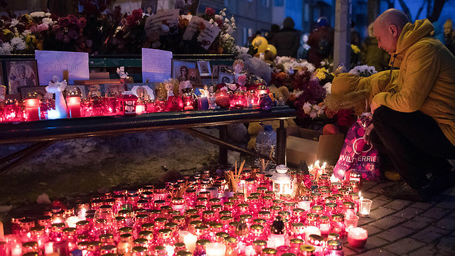 אנשים מדליקים נרות לזכר הרוגי השריפה בקניון ברוסיה (צילום: MCT)