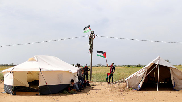 פלסטיני תולה דגל בגבול רצועת עזה (צילום: רויטרס)