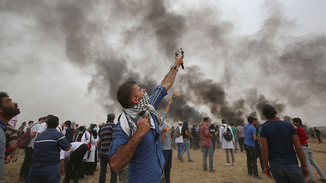 Palestinian rioter armed with slingshot aiming at a nearby hovering drone (Photo: AFP)