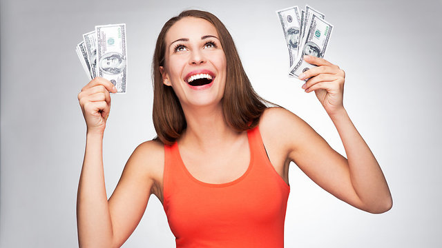 אישה מחזיקה שטרות כסף (צילום: Shutterstock)