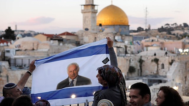 ישראלים מניפים דגל ישראל עם תמונה של בנימין נתניהו על רקע הר הבית יום ירושלים (צילום: AFP)