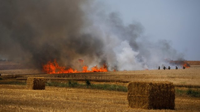 חיילים מכבים שריפה בשדה ליד קיבוץ מפלסים (צילום: רויטרס)