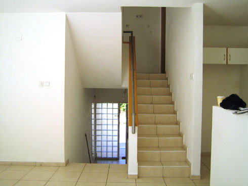 מבט ממפלס הסלון לדלת הכניסה וגרם המדרגות, לפני השיפוץ