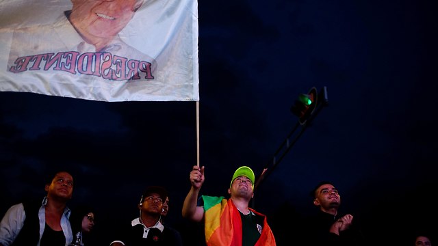 תומך של מועמד השמאל אוברדור מנופף בדגל עם תמונתו של המועמדג לאחר היוודע תוצאות  הבחירות הראשוניות במקסיקו סיטי (צילום: רויטרס)