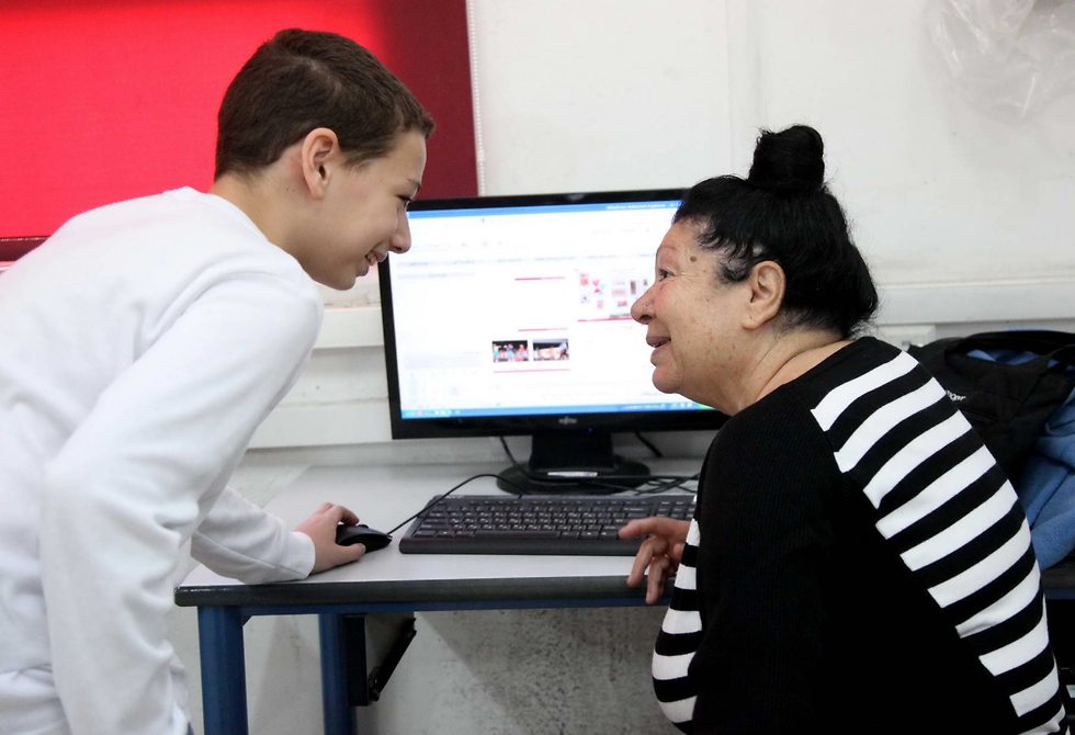נער צעיר מסביר לאישה מבוגרת כיצד מפעילים מחשב ()