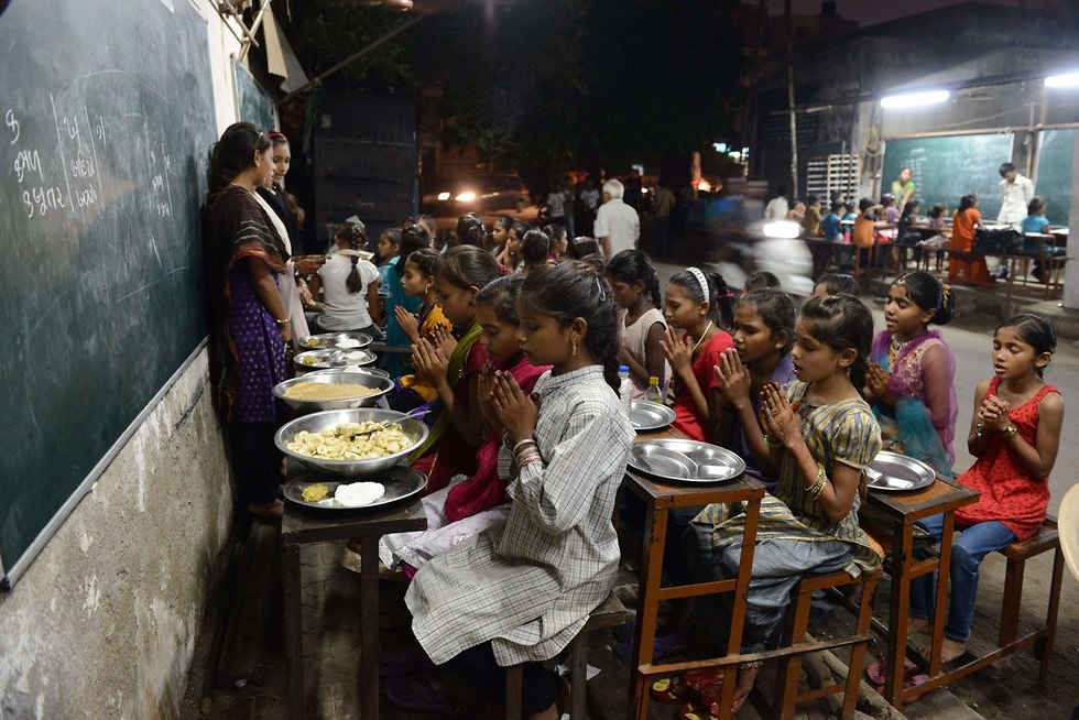 תלמידים הודים מברכים על האוכל מול הלוח (צילום: AFP)