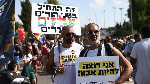 Two marchers, one with a sign saying 'It started with two parents, gay and young,' while the other's sign says: 'I want to be a father' (Photo: Ohad Zwigenberg)