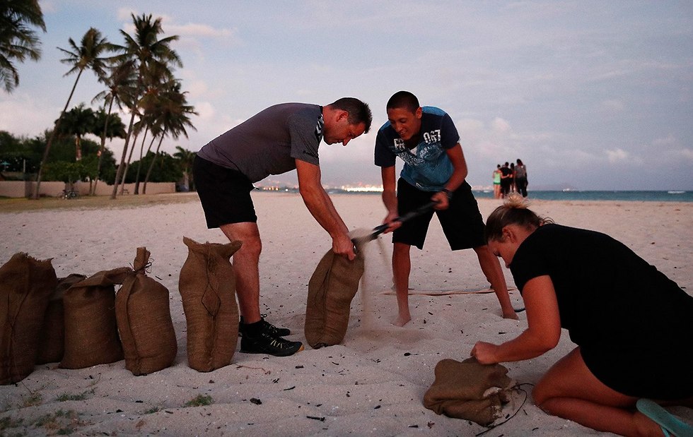 אנשים ממלאים שקי חול כדי להגן על הבית לקראת סופה הוריקן ליין הוואי ארה
