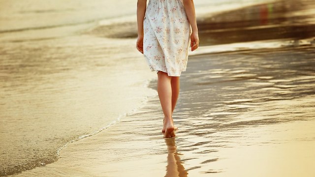 אישה צועדת על חוף הים  (צילום: Shutterstock)