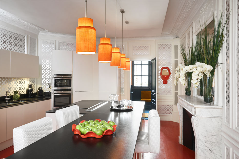 המטבח לבן, ורק הרצפה והמנורות הכתומות מזכירות את יתר חלקי הדירה. בני הבית מארחים הרבה (צילום: Rouge Absolu Designed By Geraldine Prieur)