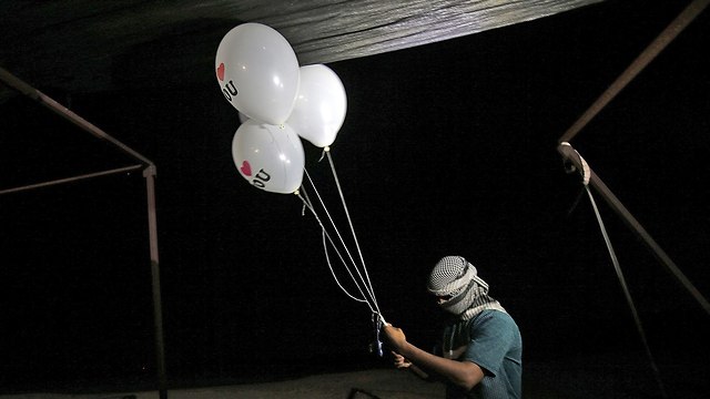 הכנה ושיגור של בלוני תבערה מעזה בלילה (צילום: AFP)