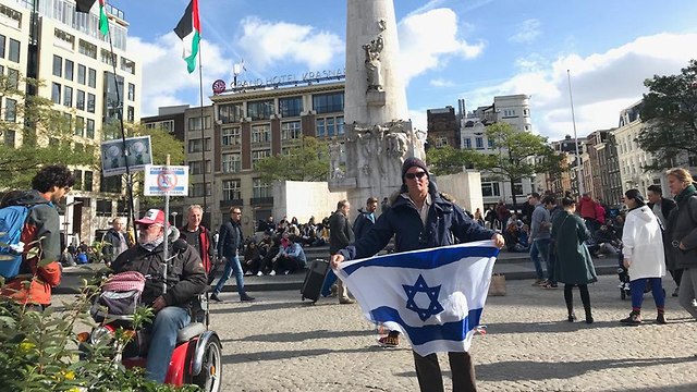 יהודי באמסטרדם שמפגין לבדו עם דגל ישראל ענק מול הפגנות הסתה של ה- BDS ()