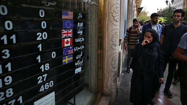 איראנים במרכז טהרן מתבונננים בשערי מטבעות שונים בחודש שעבר (צילום: AP)