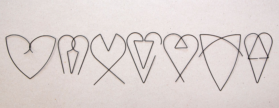 יעקב קאופמן בפרשנות קווית, תלת ממדית (מחוט ברזל שחור ודק) לצורת הלב האיקונית. כאן שבעה מתוך כמאה לבבות שהוא מציג במוז''א (צילום: הדר סייפן)