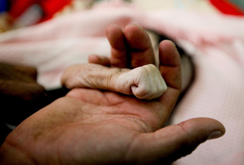 רויטרס תמונות השנה בעולם תימן סאלח חסן אל-פאקה אוחז ביד בתו בת ה-4 חודשים שמתה מתת תזונה נובמבר (צילום: רויטרס)