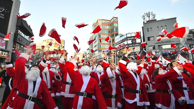 מתנדבים בבגדי סנטה קלאוס בסיאול, דרום קוריאה, זורקים כובעים באוויר לפני חלוקת מתנות (צילום: AFP)