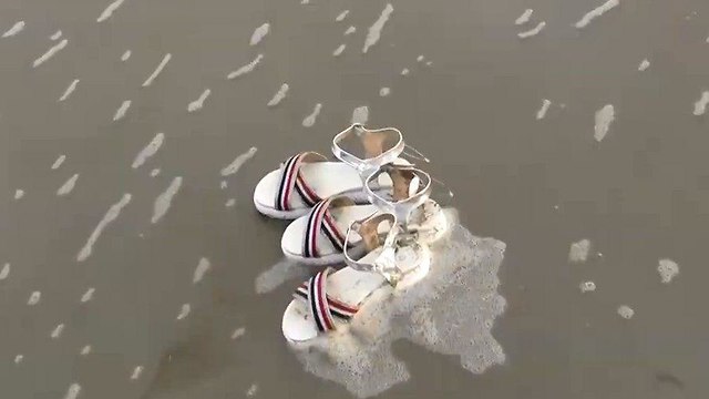 Обувь из разбитого контейнера на песчаном пляже