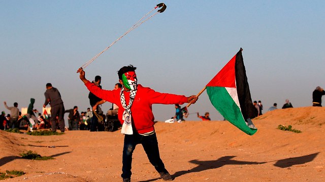 פלסטינים מפגינים מול גדר המערכת (צילום: AFP)