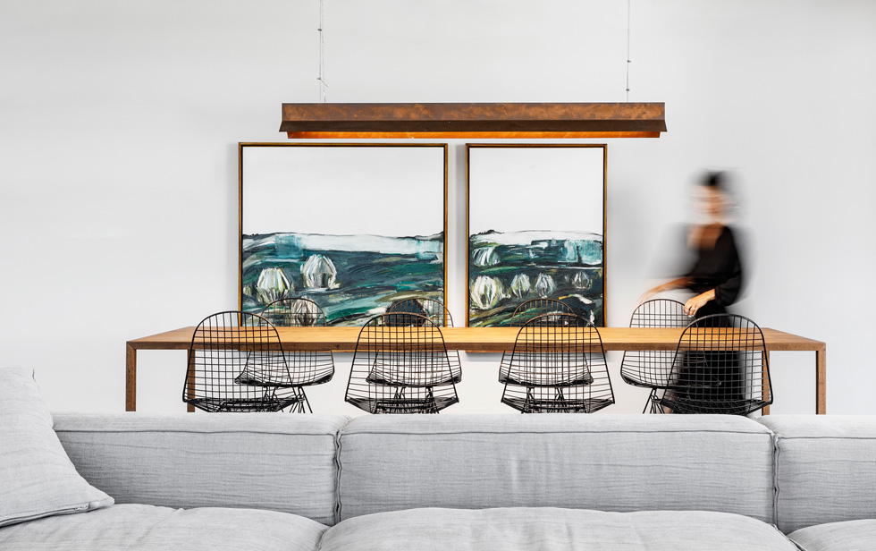 בפינת האוכל שולחן מעץ אלון, כיסאות רשת ומנורה תלויה במראה חלוד. על הקיר ציורי שמן של יהודית נוריאל-גלרמן, שהוזמנו במיוחד (צילום: איתי בנית)