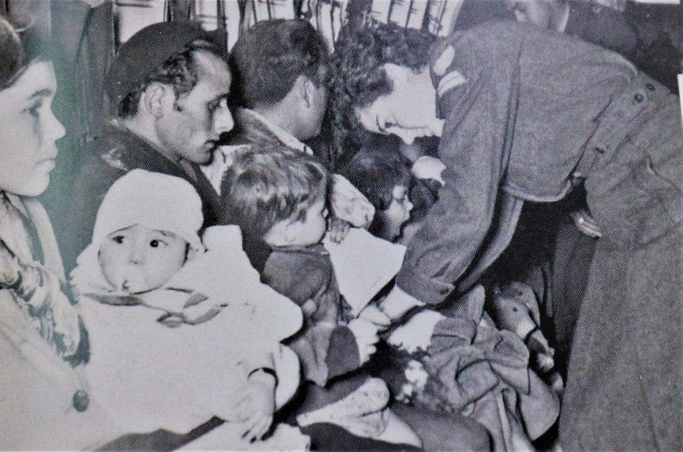 עולי מרוקו בנחיתה באילת. אלי ואשתו איטו עם התינוקת מקבלים עזרה מדיילת חיל האוויר, 1956 (צילום מתוך אלבומי רשות שדות התעופה)