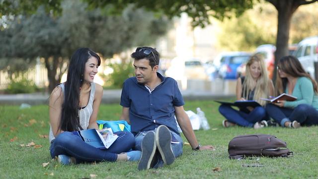 גבר ואישה יושבים על דשא ובידיהם ספרי לימוד (צילום: shutterstock)