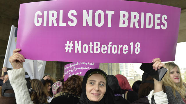 A Lebanese woman carries a placard as she takes part in a protest against child marriage in Beirut