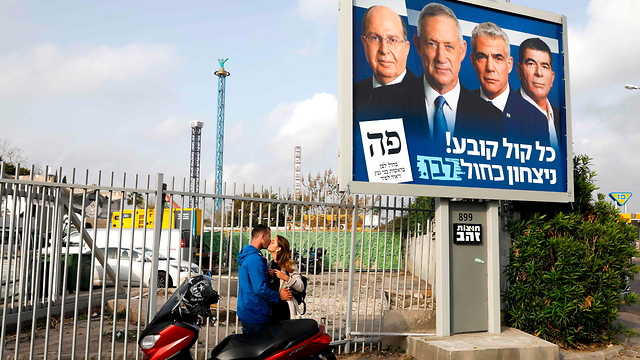 A couple kisses next to a Blue and White election poster (Photo: AFP)