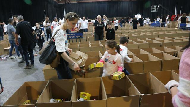 מתנדבים לאריזת חבילות מזון למשפחות נזקקות לקראת חג הפסח בהאנגר 11 בנמל תל אביב (צילום: מוטי קמחי)