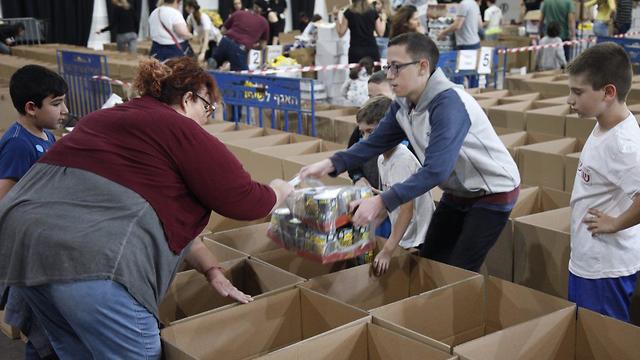 מתנדבים לאריזת חבילות מזון למשפחות נזקקות לקראת חג הפסח בהאנגר 11 בנמל תל אביב (צילום: מוטי קמחי)