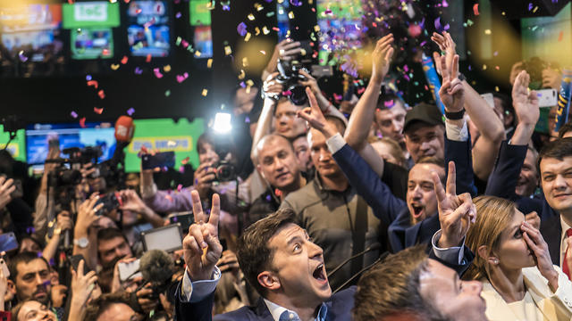 Volodymyr Zelenskiy (C) celebrates his apparent victory in Ukraine's presidential race at his election-day headquarters after polls closed on April 21