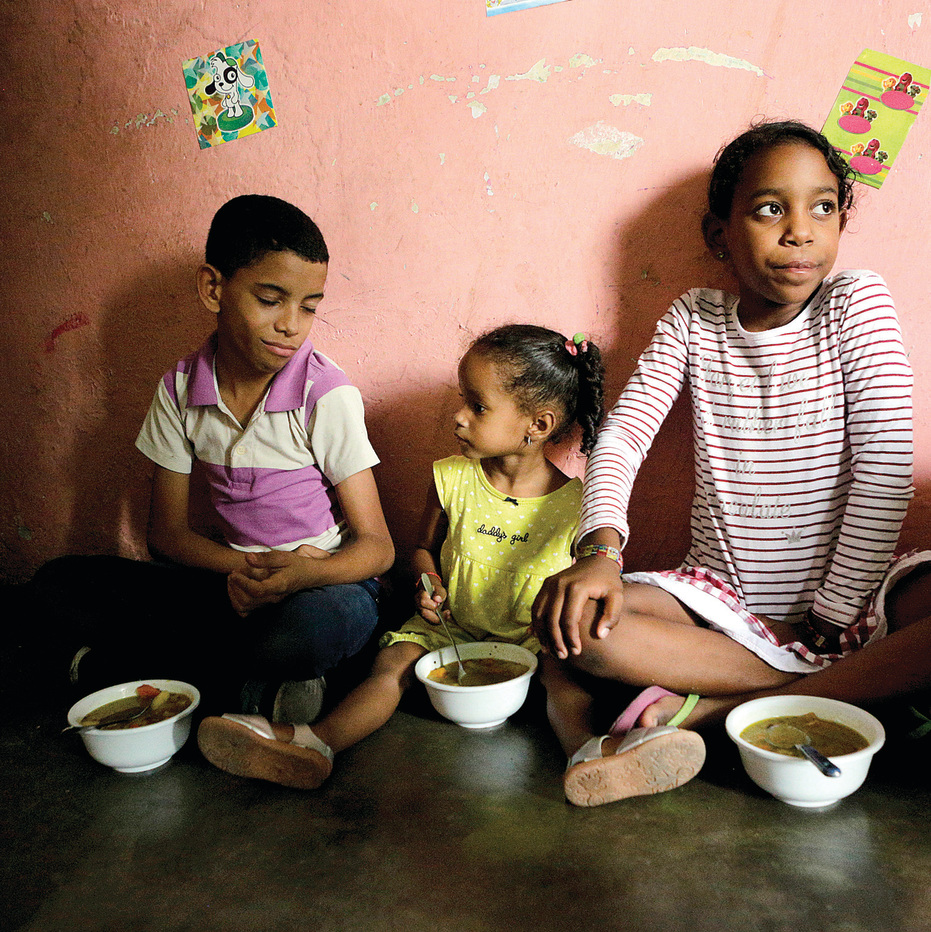 תמונות יום־יום בפטארה, הסלאם העני ביותר בקראקס: אישה מבשלת בסיר כמעט ריק, ילדים אוכלים מרק שנתרם לבית התמחוי המקומי