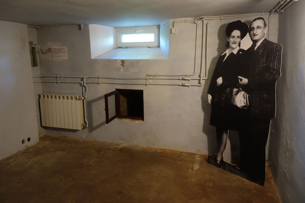 תמונת שניים מהיהודים שהסתתרו בבית ז'בינסקי, שמואל ורבקה קניגסווין, ניצבת במרתף שבו שהו. דרך הפתח הצר הם  יכלו להימלט בשעת סכנה   (צילום: מיכאל יעקובסון)