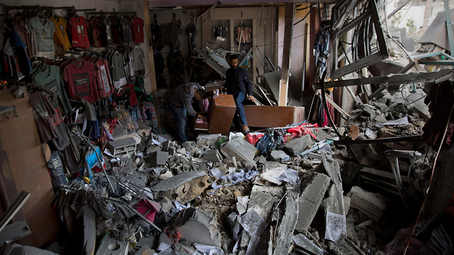 Gazans look at the damage to a shop hit by the IDF in Gaza City (Photo: AP)