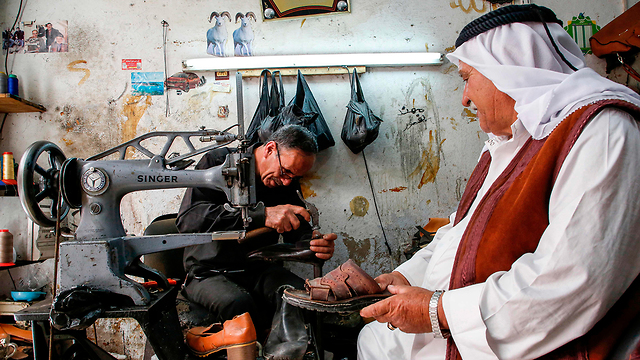 Palestinian cobbler at work in the new Hebron market (Photo: AFP)