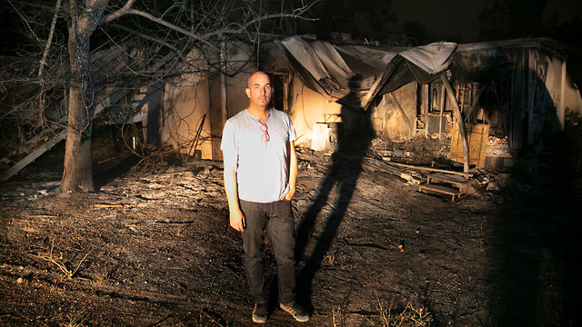 Житель кибуца Харэль у сгоревшего дома. Фото: Анер Грин